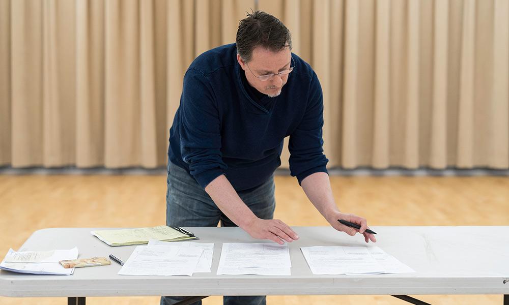 Nigel Maister, sorting through pages of a script scattered across a table.